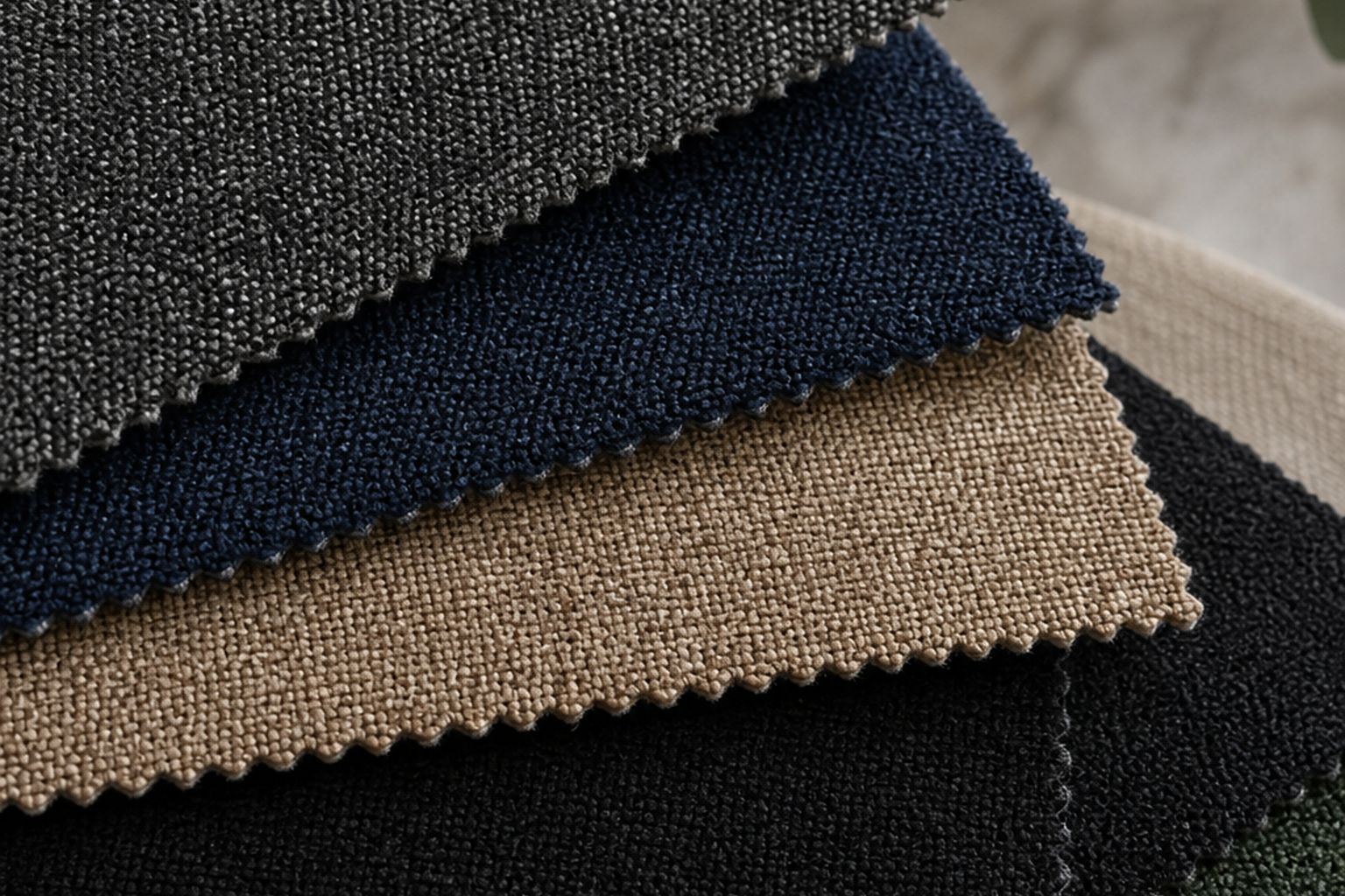 Commercial upholstery fabric swatches in charcoal, navy, tan, black, and green tight-weave textures for seating projects
